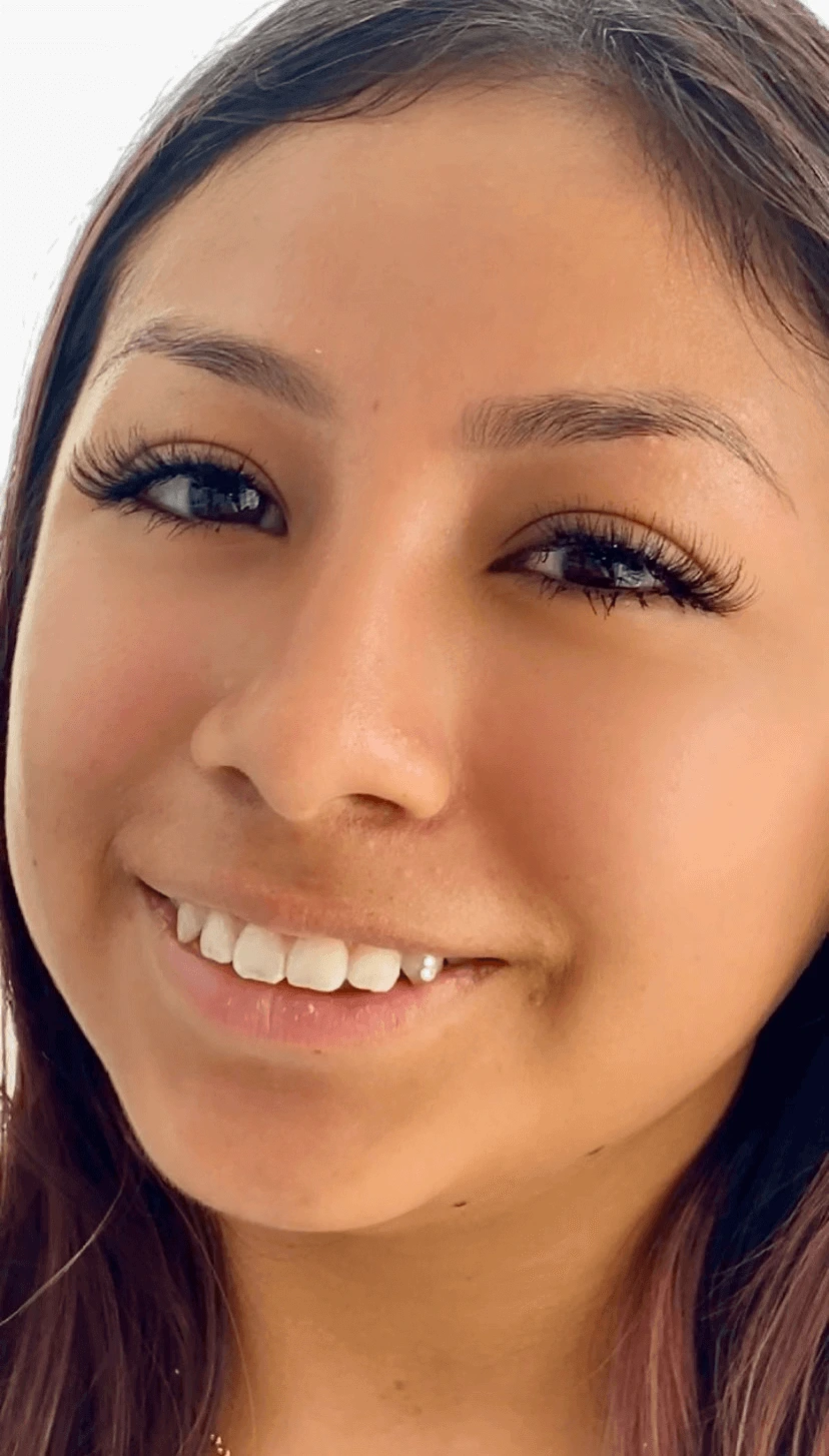 A smiling woman showcasing her decorated tooth with a gem